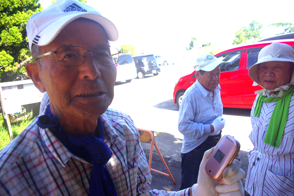青山さん。御年80歳。キュートなピンクのガラケー。