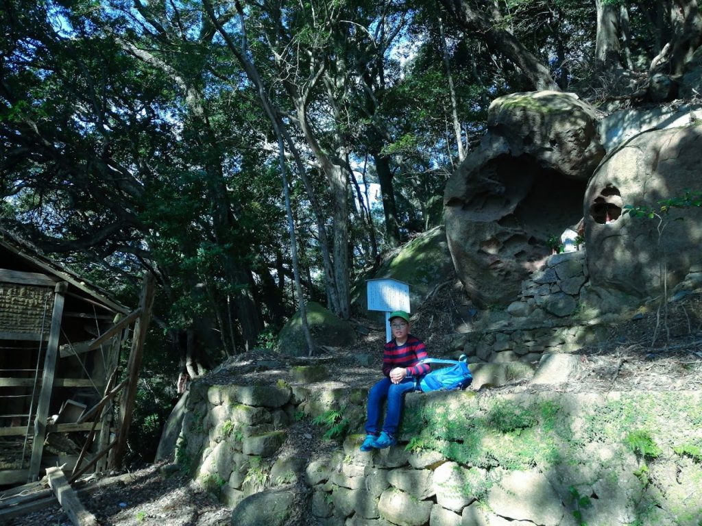 少年の右上にある岩のくぼみに泊観音がある。